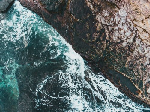 Free From above scenic view of stormy sea with rapid water streams against rough mountain in daytime Stock Photo