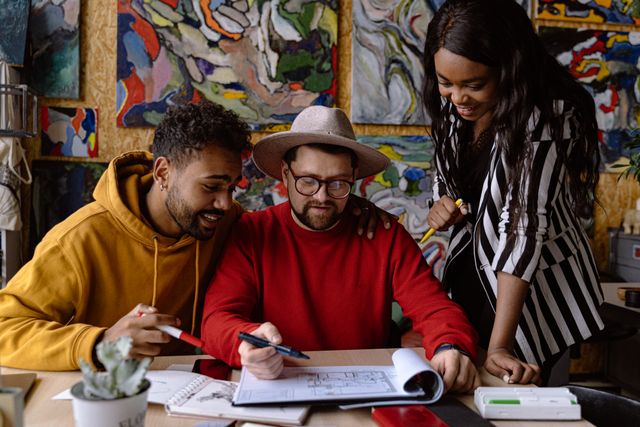 Three people reviewing drawings in an art studio — photo by Adventure Studio on Pexels