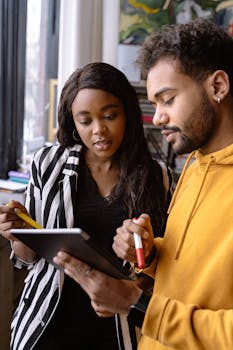 Two colleagues discussing a project using a tablet in a modern office setting.