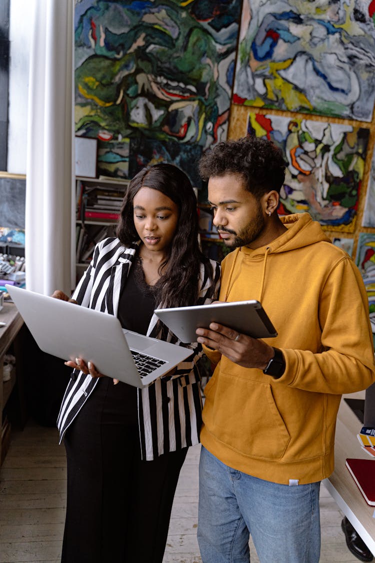 Mn And Woman In An Art Studio Using Laptop And Tablet 