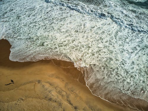 Aerial Shot of Foamy Waves on a Beach 