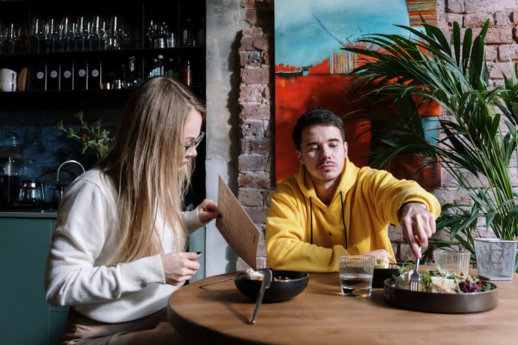 Couple Eating Dinner By Round Table At Restaurant 