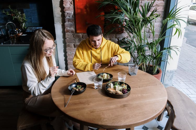 Couple Sitting In Restaurant By Window Enjoying Meal