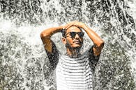 年轻人在贾夫隆瀑布下戴着墨镜，享受清爽的户外体验