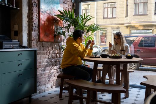 Two friends dining in a stylish cafe, enjoying casual conversation and food.