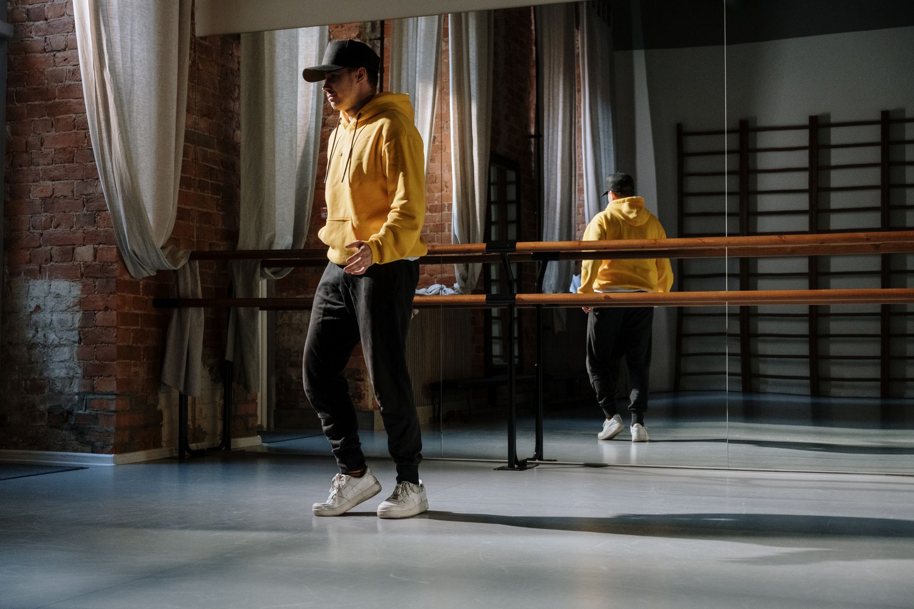 Homme en sweat à capuche jaune et pantalon noir dans un studio urbain