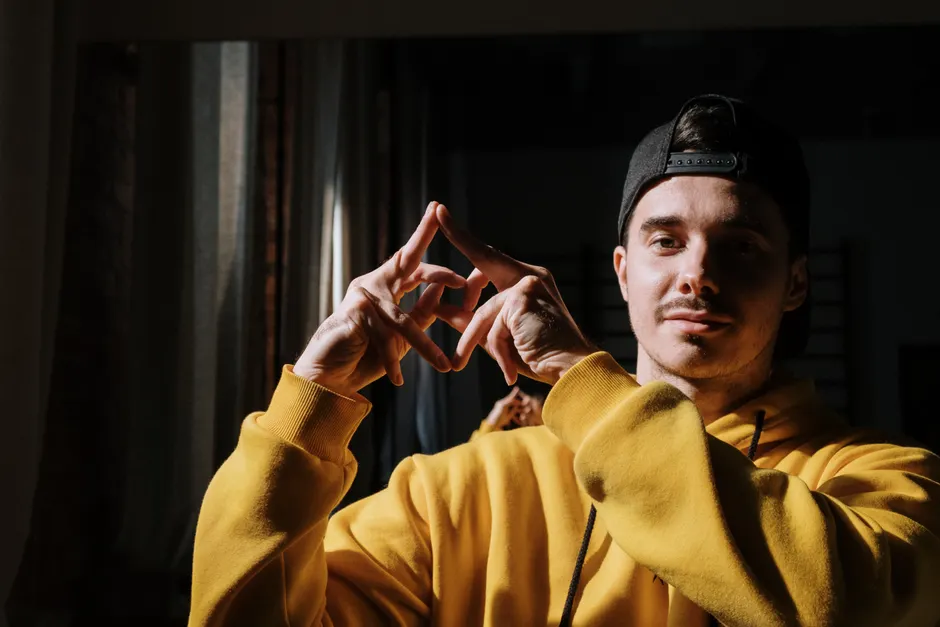 Homme en sweat jaune arborant une casquette snapback noire à visière retournée