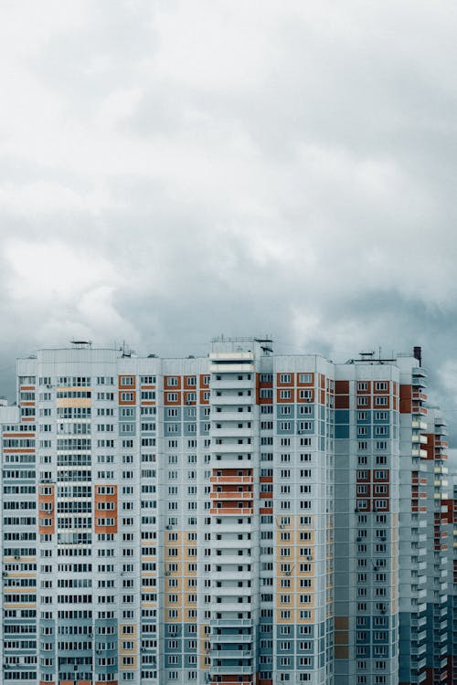 Exterior of high modern colorful residential building with balconies located in megapolis district on cloudy day in daytime