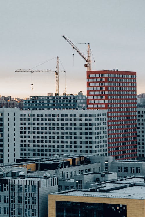 Cityscape with contemporary residential buildings and building crane on cloudy day