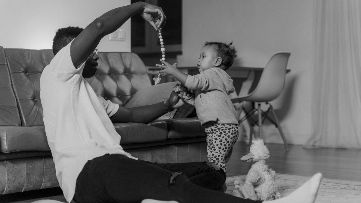 A father and child bonding while playing indoors, creating a warm family moment.