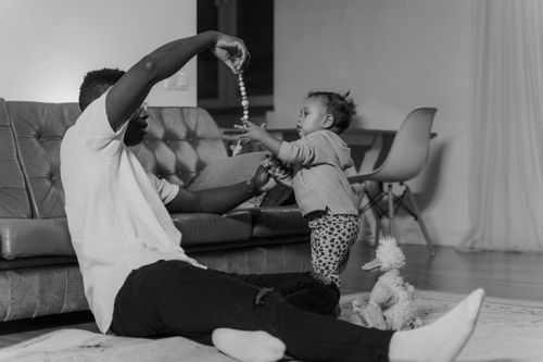 Free A father and child bonding while playing indoors, creating a warm family moment. Stock Photo