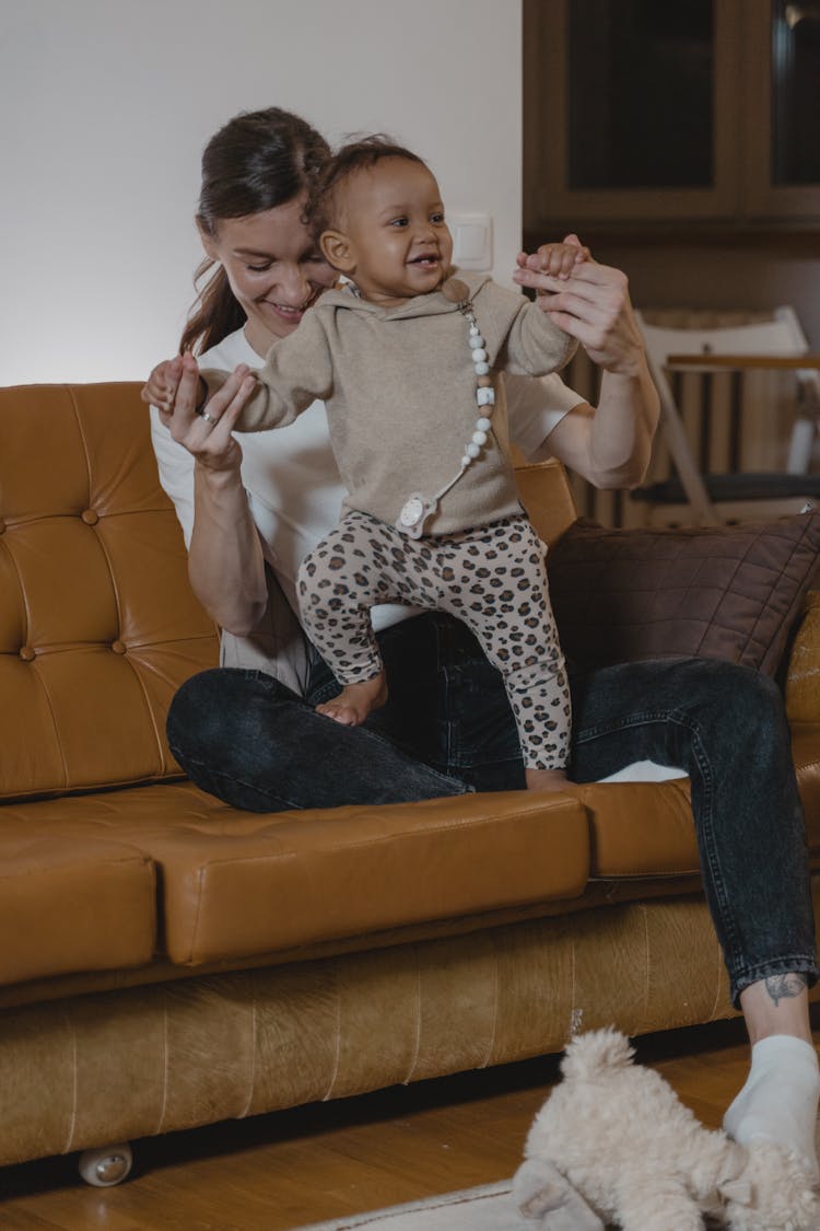 A Woman Playing With Her Young Daughter On A Couch