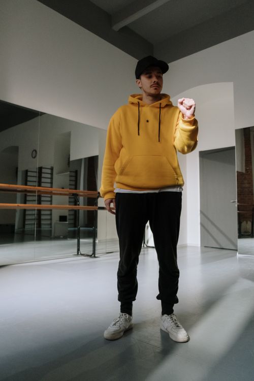 Free Man in stylish outfit posing in a bright dance studio, showcasing urban fashion. Stock Photo
