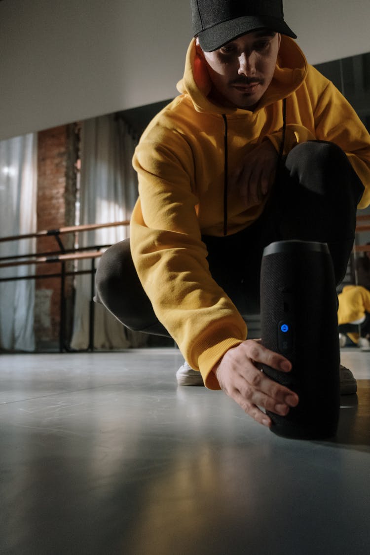 A Man In Yellow Hoodie Putting The Wireless Speaker On The Floor