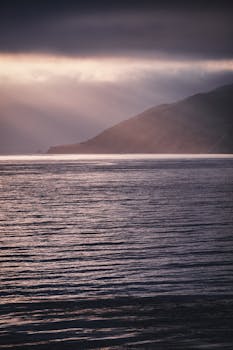 Scenic view of the ocean and mountains under dramatic sunset lighting.
