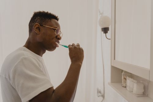Free Man brushing his teeth in a bathroom, focusing on daily oral care and hygiene. Stock Photo
