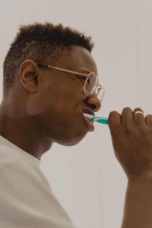 Free Side view of a young man brushing his teeth, promoting daily oral hygiene habits. Stock Photo