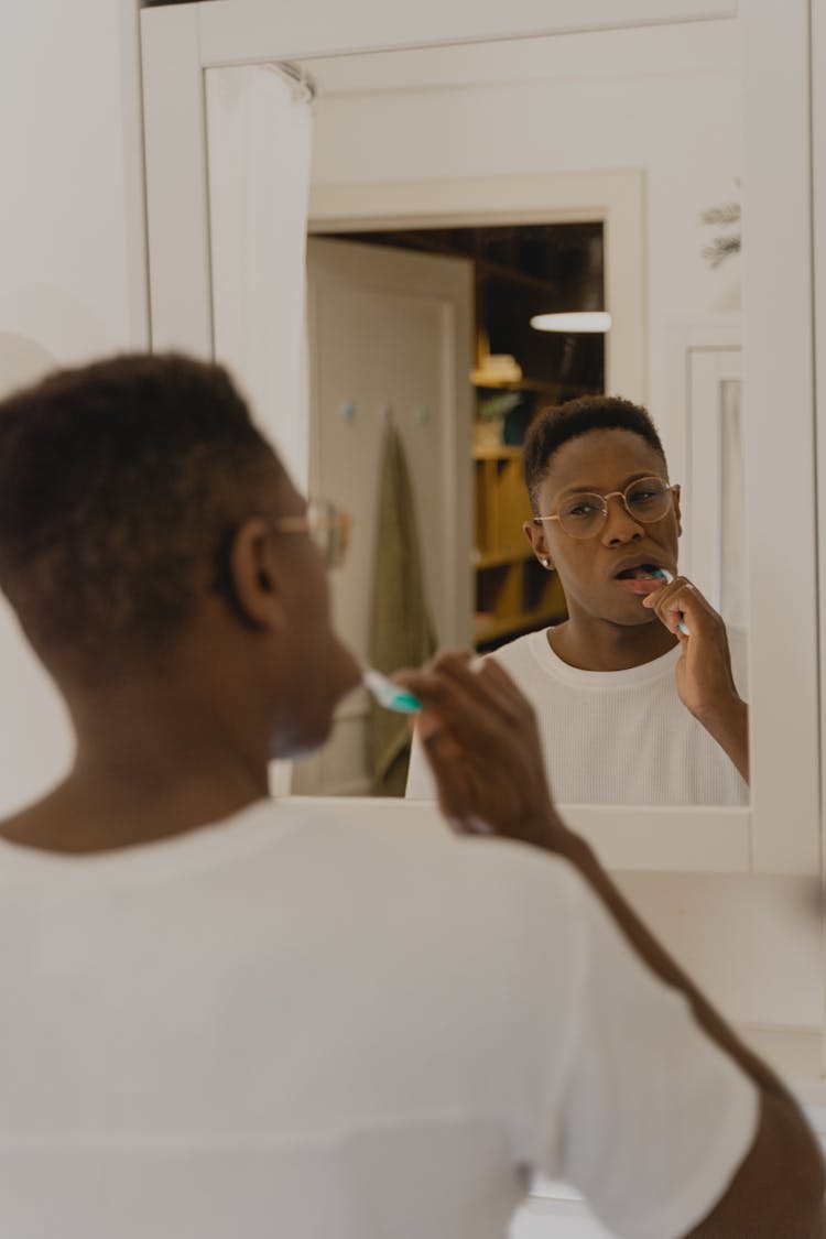 A Reflection Of A Man Brushing His Teeth