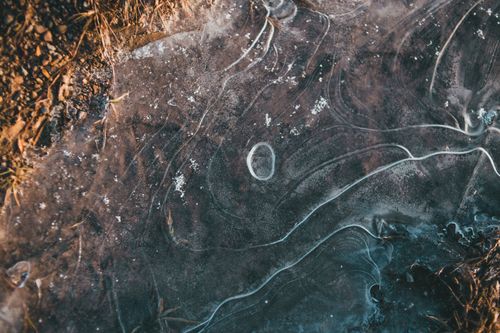 Free Top view of frozen surface of small puddle on dry rough rural road on sunny day Stock Photo