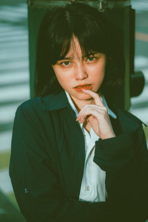 Free Alluring young Asian lady touching lips while standing on street Stock Photo