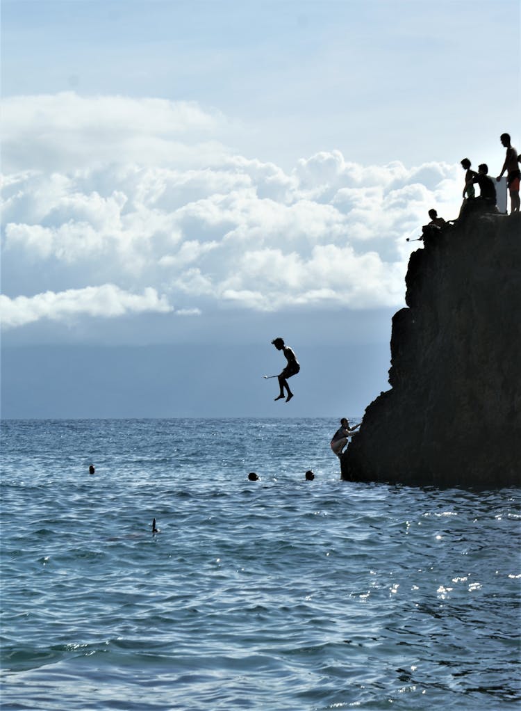 People Jumping Off A Cliff Into The Sea 