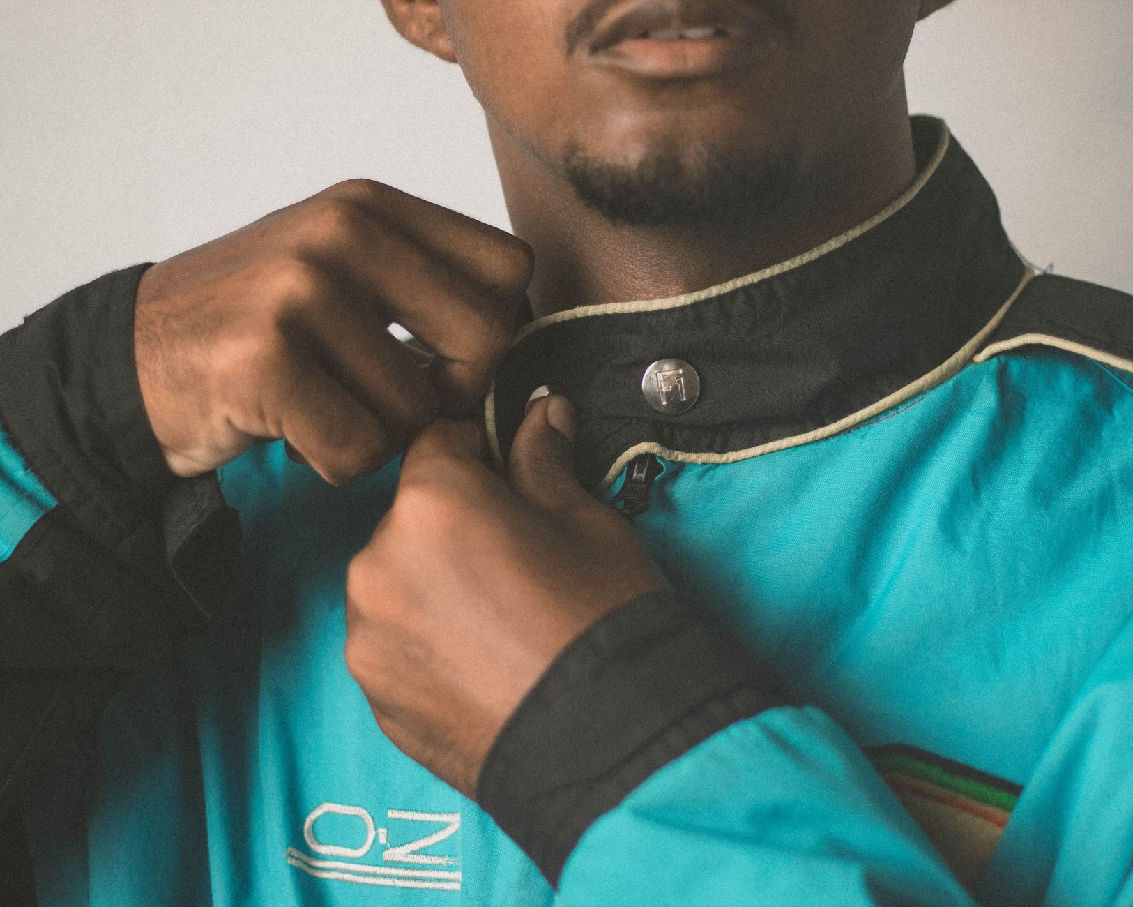 A detailed close-up of a man adjusting his blue jacket's collar, focusing on hands and clothing.