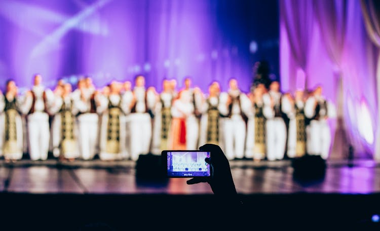 Person Recording Performance On Stage Using Phone 