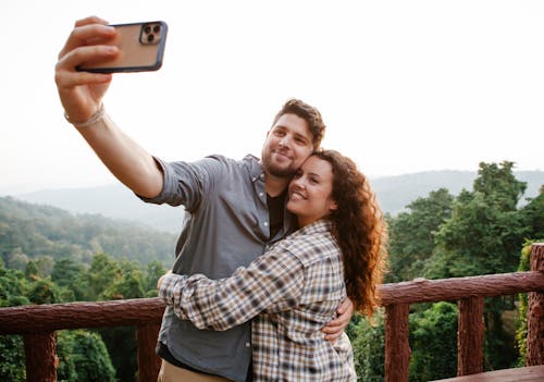 Free Cheerful young couple hugging while taking selfie on terrace in forest Stock Photo