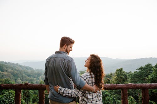 Free Smiling young couple embracing on terrace and admiring nature Stock Photo