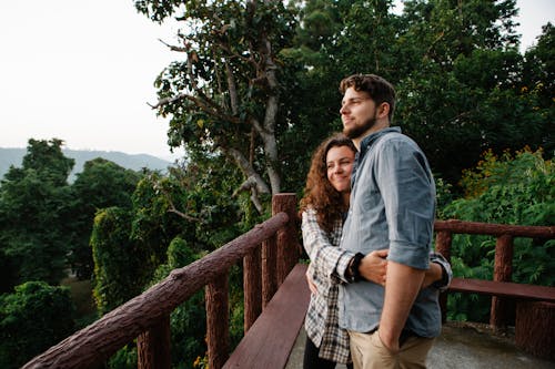 Free Positive young traveling couple admiring nature from wooden terrace Stock Photo