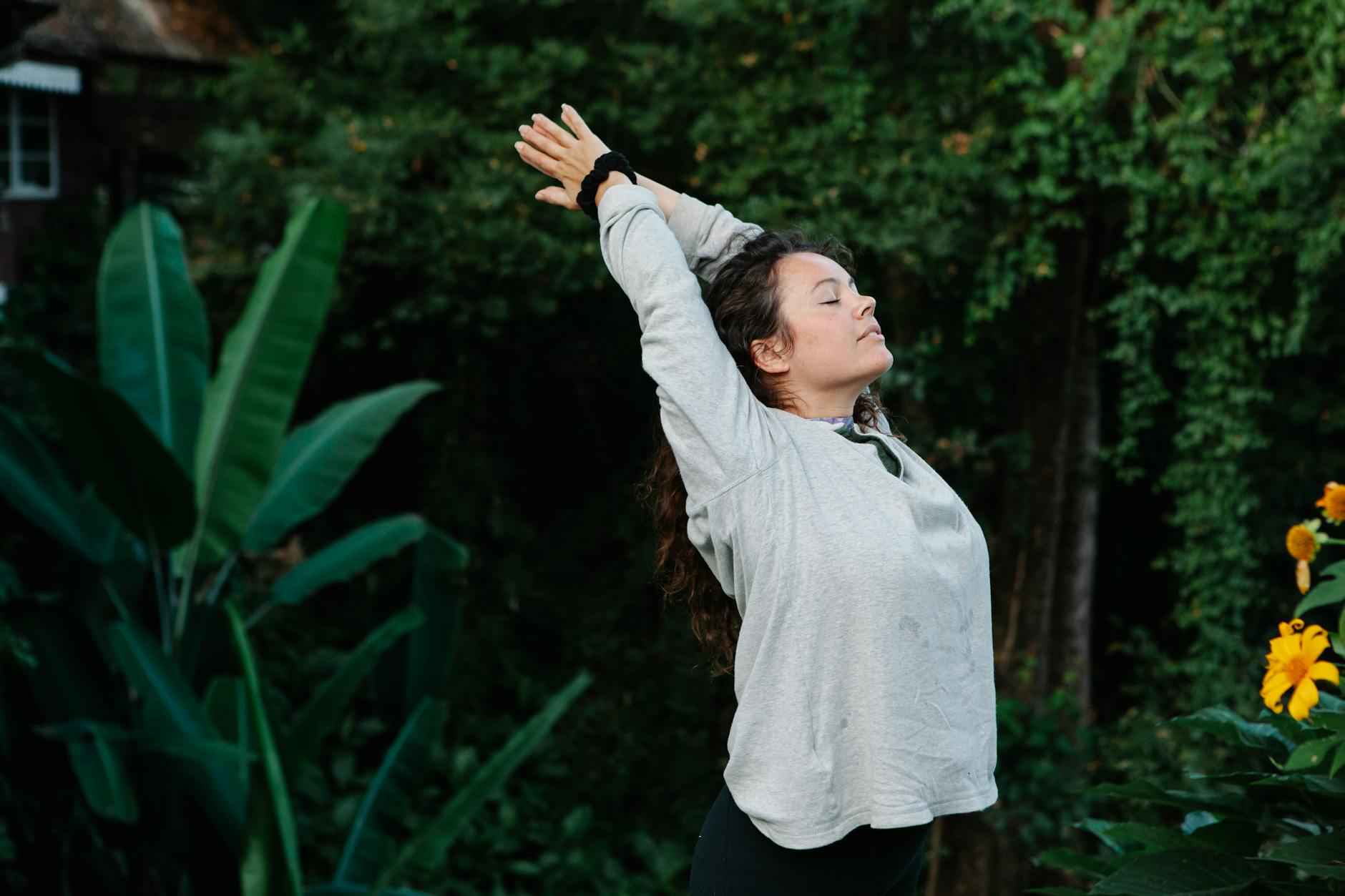 Woman with eyes closed stretching among green tropical trees · Free ...