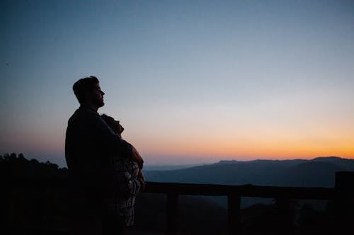 日没時に橋の上に立っている黒と白の格子縞のドレスシャツの男