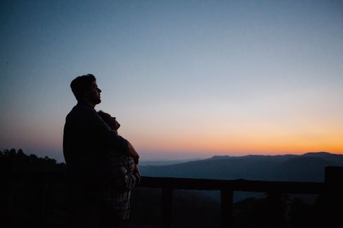 Free Side view of cheerful loving couple hugging in orange sunset in rough rocky mountains Stock Photo
