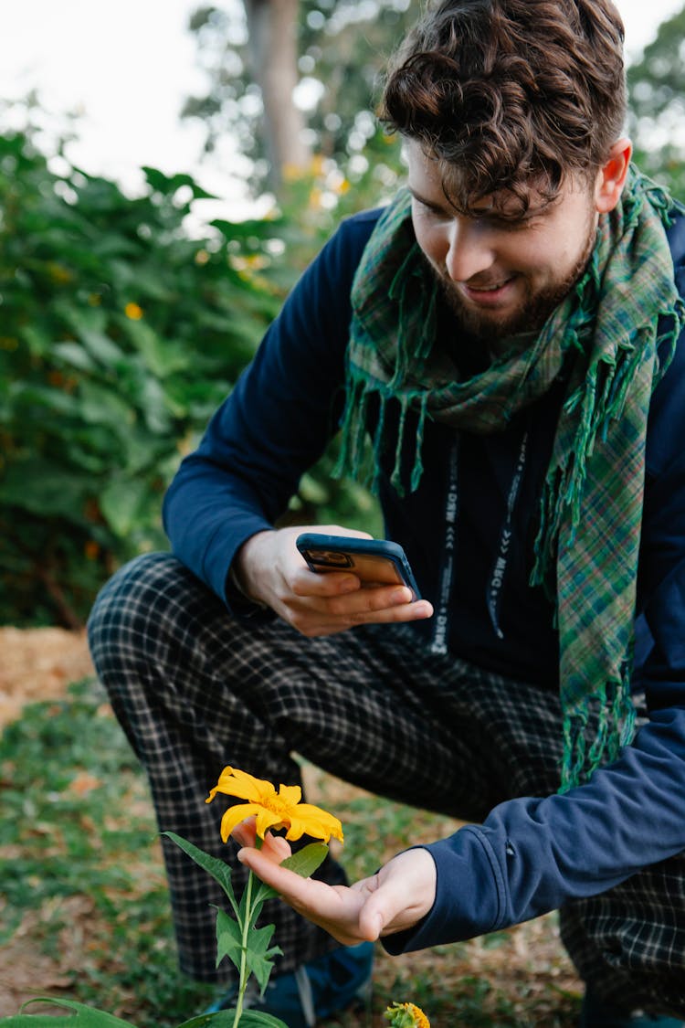 Man In Trendy Outfit Taking Photo Of Flower With Smartphone
