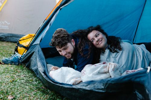 Free Young happy couple enjoying vacation together while having rest in tent in nature Stock Photo