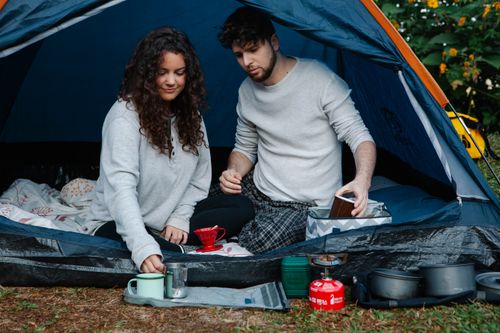 Free Young smiling couple in pyjamas making breakfast sitting in tent while spending holidays together in countryside Stock Photo