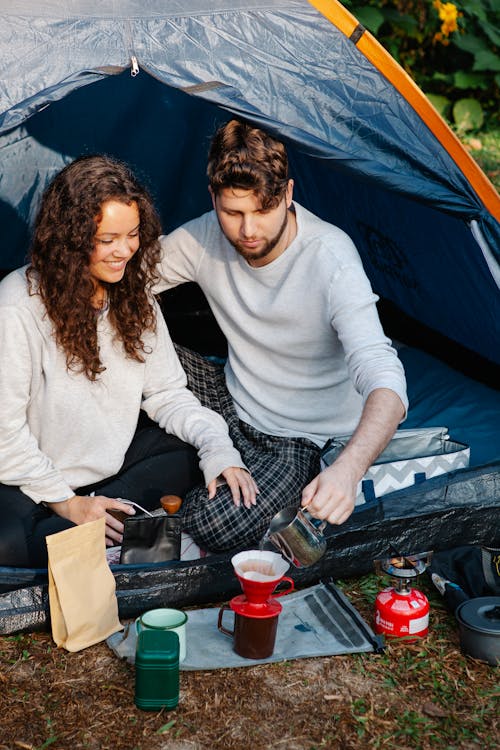 Couple of travelers brewing coffee in tent