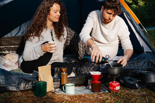 Free Crop hikers preparing hot drink in campsite Stock Photo