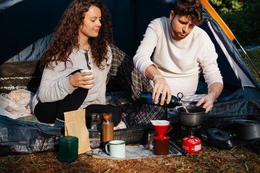 Crop hikers preparing hot drink in campsite