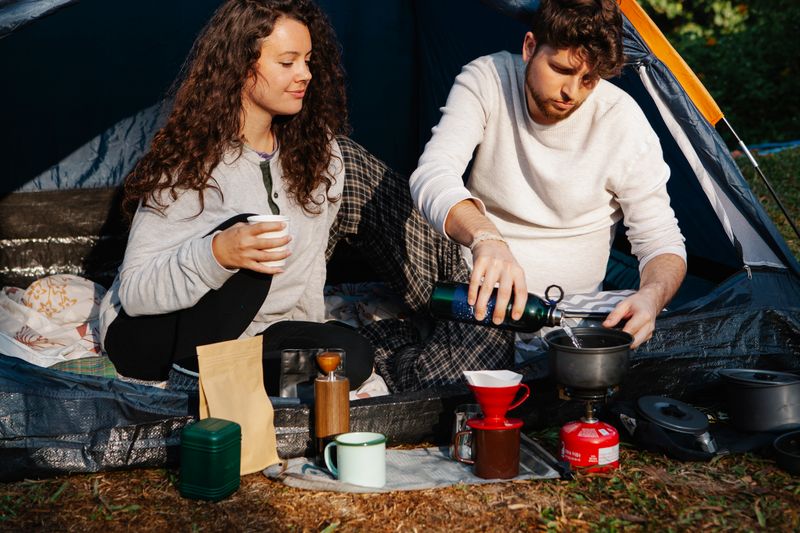 Couple making pour-over coffee together at a campsite, a simple outdoor date idea for Norwegian singles