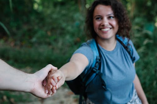Free Crop cheerful backpacker holding hand of boyfriend during hike Stock Photo