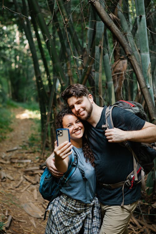 Romantic young couple smiling while taking selfie during hike in forest