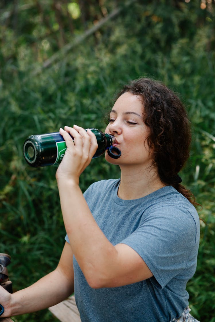 Tired Young Woman Drinking Water During Hiking Trip In Forest