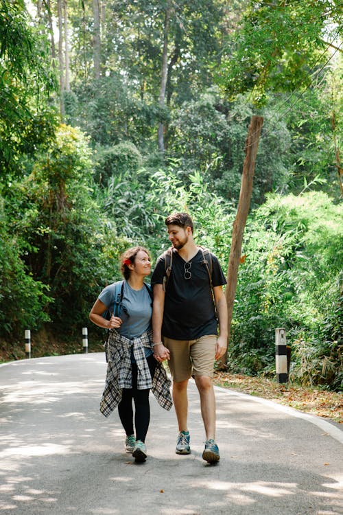Free Romantic couple holding hands and walking on path in jungle Stock Photo