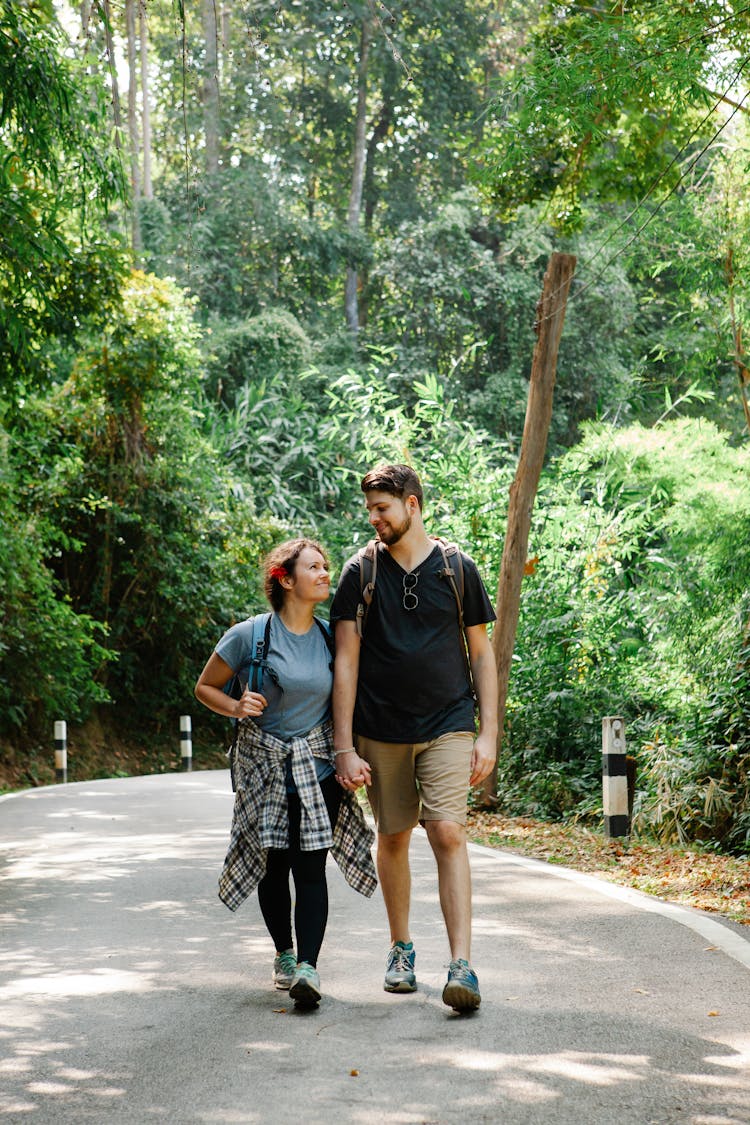 Romantic Couple Holding Hands And Walking On Path In Jungle