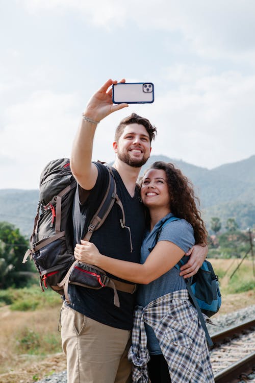 Couple of travelers taking selfie on smartphone near grassy valley