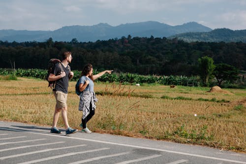 Couple of travelers walking along road in countryside during trip
