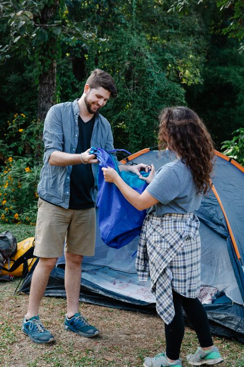 Free Content bearded male hiker with anonymous girlfriend and rucksack talking against tent during summer trip Stock Photo