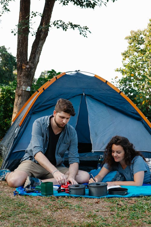 Content young couple resting on plaid near camping tent in nature