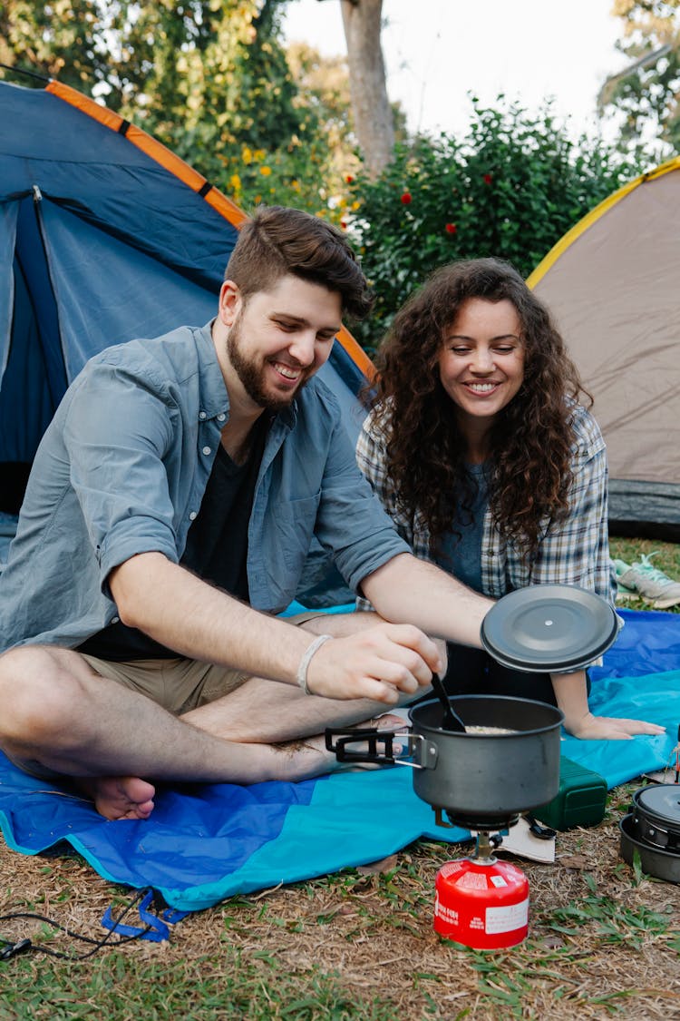 Man And Woman Cooking Near The Tents 